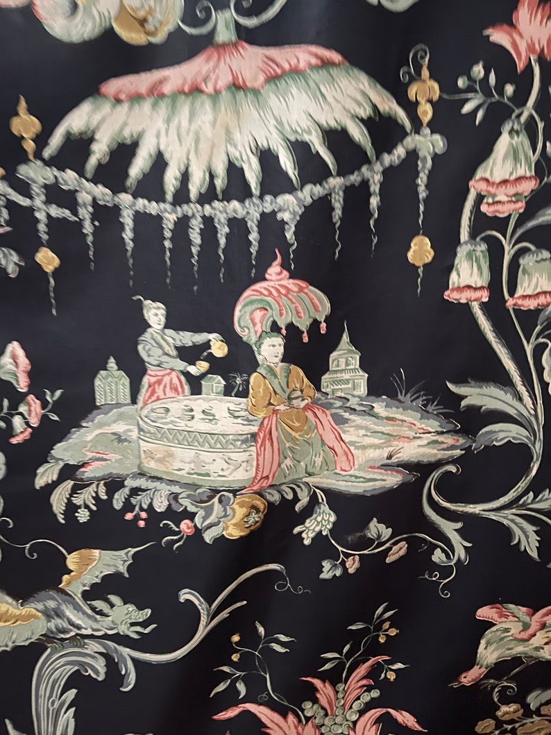 May include: A black fabric with a repeating pattern of stylized flowers, plants, and figures. The figures are dressed in pink, green, and yellow clothing. The fabric has a vintage feel.