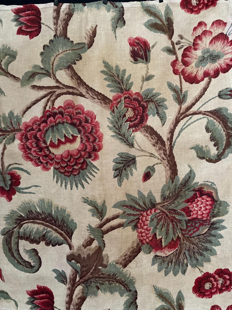 May include: A vintage floral fabric with a repeating pattern of red and green flowers on a cream background. The flowers are stylized and have a slightly faded look.