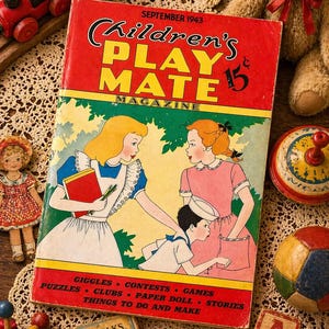 May include: Vintage "Children's Play Mate" magazine from September 1943, featuring illustrations of children. The cover is red with yellow and green accents. Other toys include a wooden train, a teddy bear, a spinning top, and alphabet blocks.