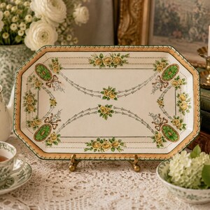 May include: An octagonal ceramic serving tray featuring a cream-colored center with yellow rose clusters, green oval medallions, and brown ribbon motifs. The tray has a wide, textured tan border with a dark green edge and a decorative trim.