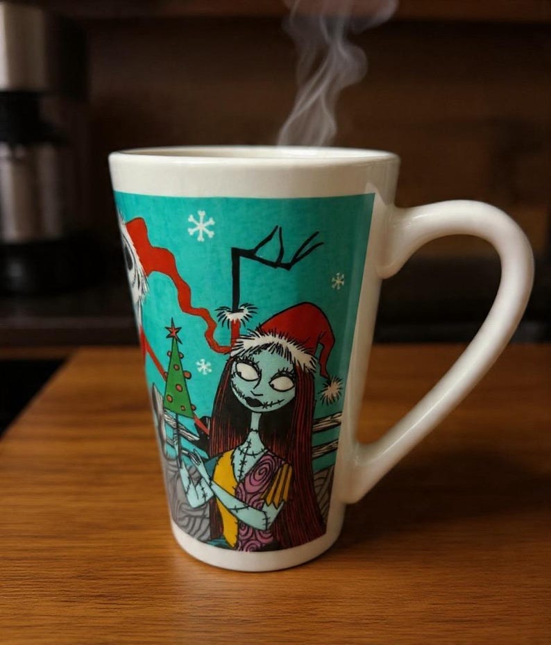Może przedstawiać: Biały ceramiczny kubek o zwężanym kształcie z turkusowym tłem i grafiką przedstawiającą Sally z Miasteczka Halloween w czapce Mikołaja, z unoszącą się parą oraz białymi akcentami w kształcie płatk&oacute;w śniegu na powierzchni kubka.