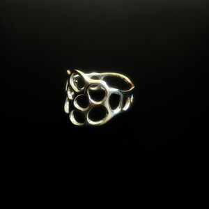 May include: A silver ring with a unique, abstract design featuring a series of interconnected circles.