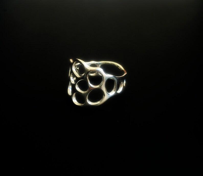 May include: A silver ring with a unique, abstract design featuring a series of interconnected circles.