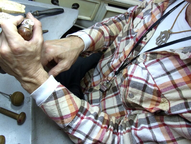 May include: A person wearing a red and white plaid shirt with a black lanyard and a silver skull pendant. The lanyard has the word "NOKIA" printed on it.