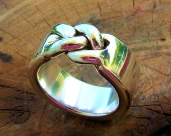 May include: A silver ring with a knot design. The knot is made of three strands of silver that are intertwined.
