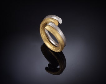 May include: A gold and silver ring with a twisted design. The ring is made of two bands that are intertwined.