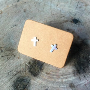 May include: A pair of silver cross stud earrings on a brown card.