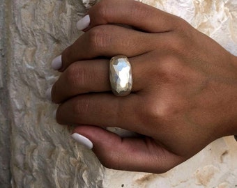 May include: A silver ring with a hammered, textured finish. The ring is wide and has a rounded shape.