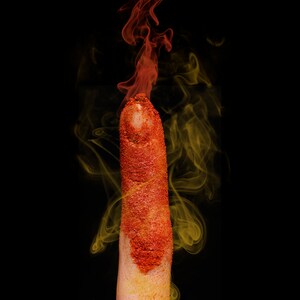 May include: A finger covered in red glitter with yellow smoke rising from the tip.
