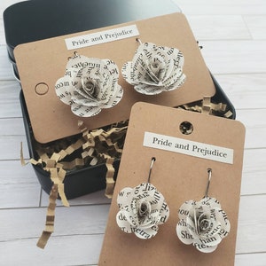 May include: Two pairs of earrings featuring paper roses made from pages of the book "Pride and Prejudice". The earrings are displayed on brown cards with the book title printed on them.