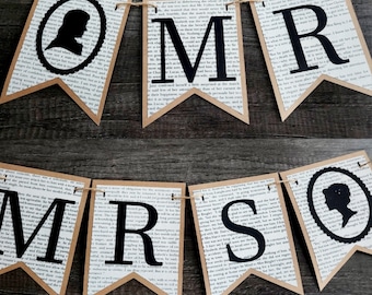 May include: A brown paper banner with black letters spelling out "MR. & MRS."  Each letter is on a separate pennant.  The pennants have a silhouette of a woman's head in a circle on each end.