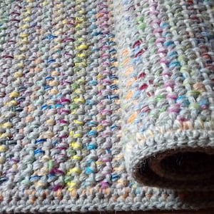 Può includere: Un tappeto all'uncinetto grigio e multicolore arrotolato con una superficie testurizzata.