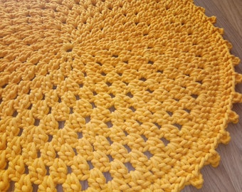 May include: A round, yellow crocheted rug with a textured, woven pattern.