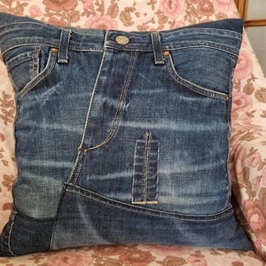 Op de afbeelding: Een blauw denim kussen met een patchwork ontwerp. Het kussen is gemaakt van gerecycled denim en heeft een unieke, verweerde look.