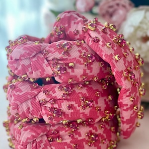 May include: A stack of pink and white patterned hair scrunchies with pink and gold embellishments.