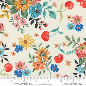 May include: White fabric with a repeating pattern of red cherries, yellow and orange flowers, blue flowers, and green leaves. The fabric has a ruler with the word "moda" printed on it.