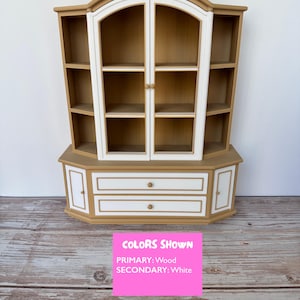 May include: A wooden cabinet with glass doors and two drawers. The cabinet is painted in a light brown color with white trim. The cabinet has a curved top and bottom.