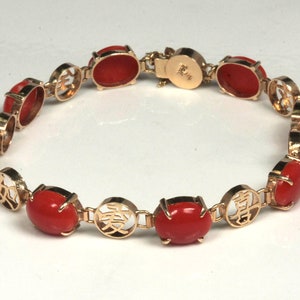 May include: A gold bracelet with red coral stones and Chinese characters. The bracelet has a clasp with the number "14K" on it.