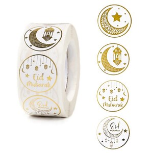 May include: Roll of white round stickers with gold foil designs. The stickers feature a crescent moon, star, and lantern with the text "Eid Mubarak".