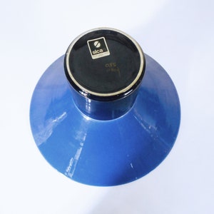 K&ouml;nnte beinhalten: Eine blaue Keramikvase mit schwarzem Rand und einem schwarzen Etikett mit der Aufschrift "Sica 085 Italien".