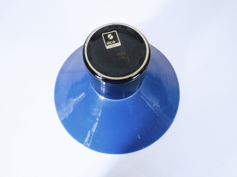 K&ouml;nnte beinhalten: Eine blaue Keramikvase mit schwarzem Rand und einem schwarzen Etikett mit der Aufschrift "Sica 085 Italien".