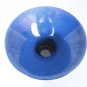 K&ouml;nnte beinhalten: Eine blaue Keramikvase mit einer breiten, ausgestellten &Ouml;ffnung und einem schmalen Boden. Die Vase hat eine glatte, gl&auml;nzende Oberfl&auml;che.