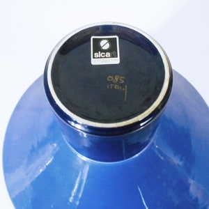 K&ouml;nnte beinhalten: Blaue Keramikvase mit breiter Basis und schmalem Hals. Der Boden der Vase hat ein schwarzes Etikett mit dem Text "sicart" und "085 ITALIA".