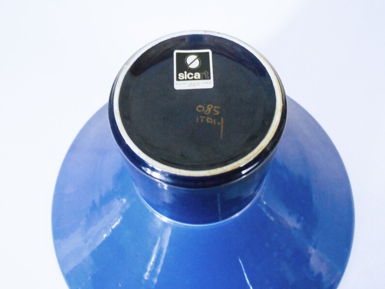 K&ouml;nnte beinhalten: Blaue Keramikvase mit breiter Basis und schmalem Hals. Der Boden der Vase hat ein schwarzes Etikett mit dem Text "sicart" und "085 ITALIA".