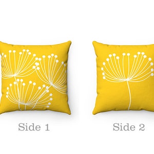 May include: Two yellow throw pillows with white dandelion designs. One pillow has a single dandelion design, while the other has multiple dandelions.