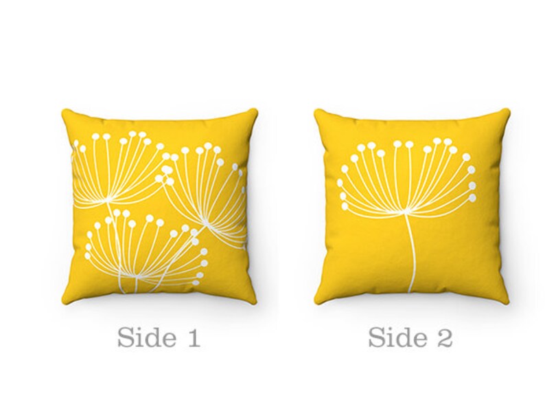 May include: Two yellow throw pillows with white dandelion designs. One pillow has a single dandelion design, while the other has multiple dandelions.