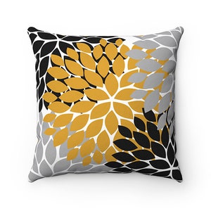 May include: A decorative throw pillow with a floral pattern in shades of gold, black, and gray. The pillow features a repeating pattern of stylized leaves.