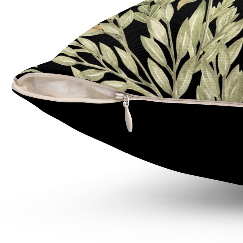 May include: A black throw pillow with a zipper closure. The pillow features a green and white floral pattern.