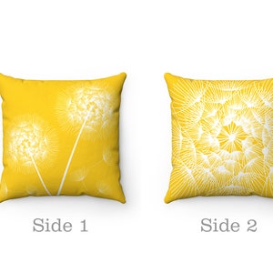 May include: Two-sided yellow throw pillow with a white dandelion design. One side features a single dandelion with seeds blowing in the wind, while the other side features a cluster of dandelions.