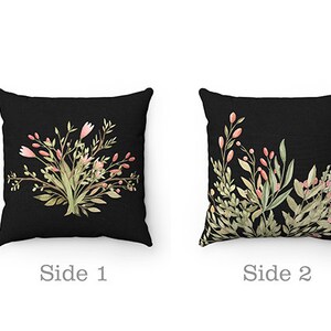 May include: Two-sided throw pillow with a black background and floral designs. One side features a bouquet of pink and green flowers. The other side features a leafy design with pink flowers.