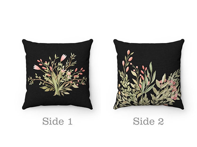 May include: Two-sided throw pillow with a black background and floral designs. One side features a bouquet of pink and green flowers. The other side features a leafy design with pink flowers.