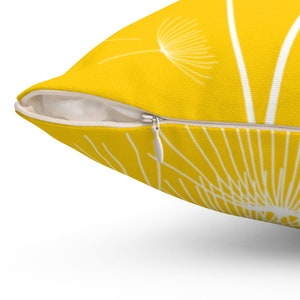 May include: A yellow throw pillow with a white dandelion design. The pillow has a zipper closure.