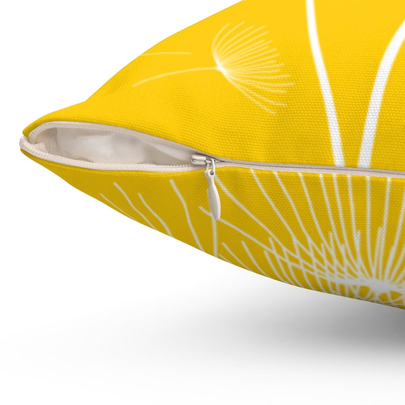 May include: A yellow throw pillow with a white dandelion design. The pillow has a zipper closure.