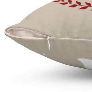 May include: A beige throw pillow with a zipper closure. The pillow has a red leaf design on the front.