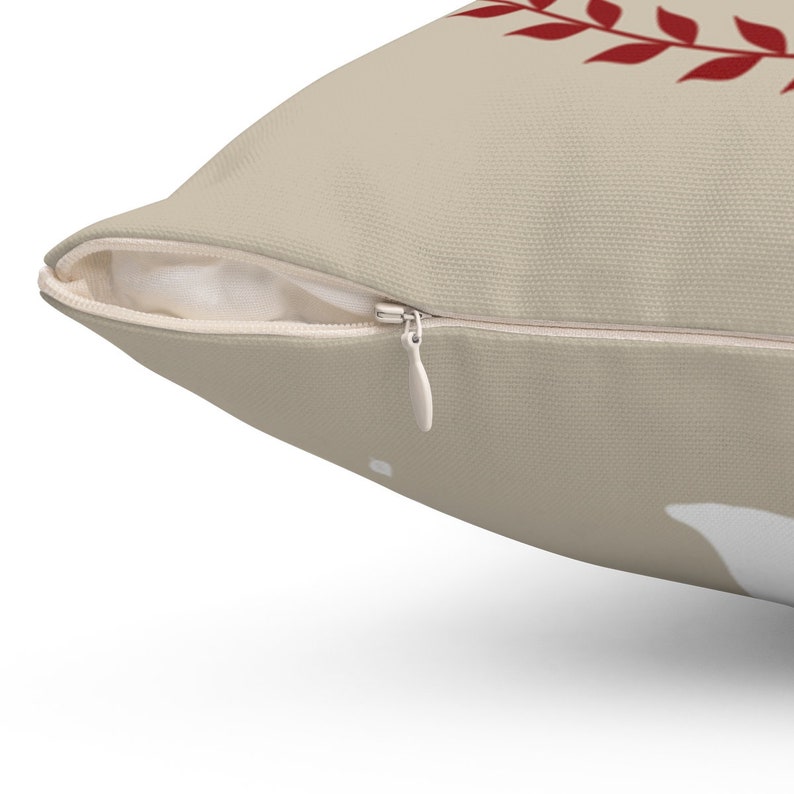 May include: A beige throw pillow with a zipper closure. The pillow has a red leaf design on the front.