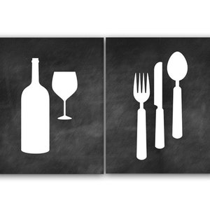 May include: Two black chalkboard signs with white silhouettes of a wine bottle and glass on one side and a fork, knife, and spoon on the other.
