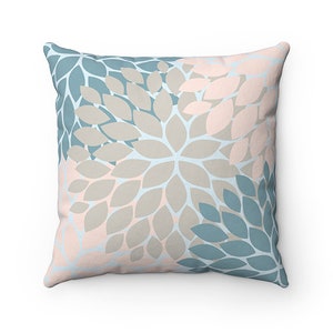 Puede incluir: Una almohada decorativa con un patr&oacute;n floral en tonos azules, rosas y grises. La almohada presenta un patr&oacute;n repetitivo de p&eacute;talos superpuestos.
