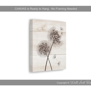 May include: A white wood background with a black and white line drawing of two dandelion flowers with seeds blowing in the wind.