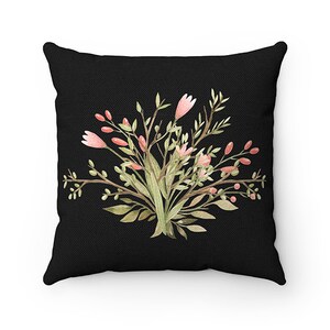 May include: A black throw pillow with a floral design featuring pink flowers and green leaves. The pillow is made of a soft, comfortable fabric.