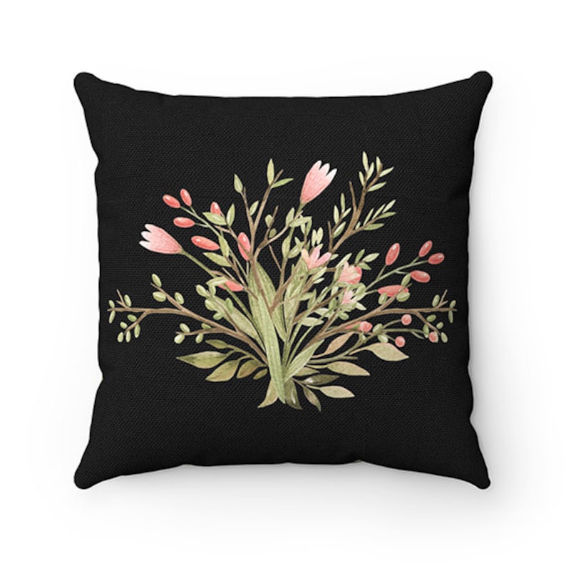 May include: A black throw pillow with a floral design featuring pink flowers and green leaves. The pillow is made of a soft, comfortable fabric.