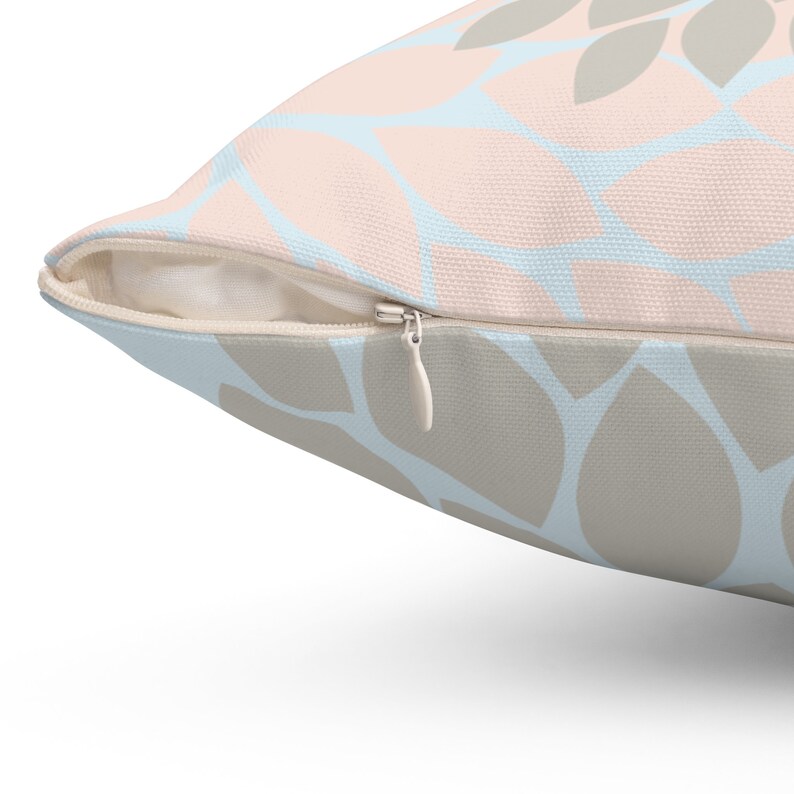 Puede incluir: Una almohada de tiro de color azul claro y beige con un patr&oacute;n de hojas. La almohada tiene una cremallera.