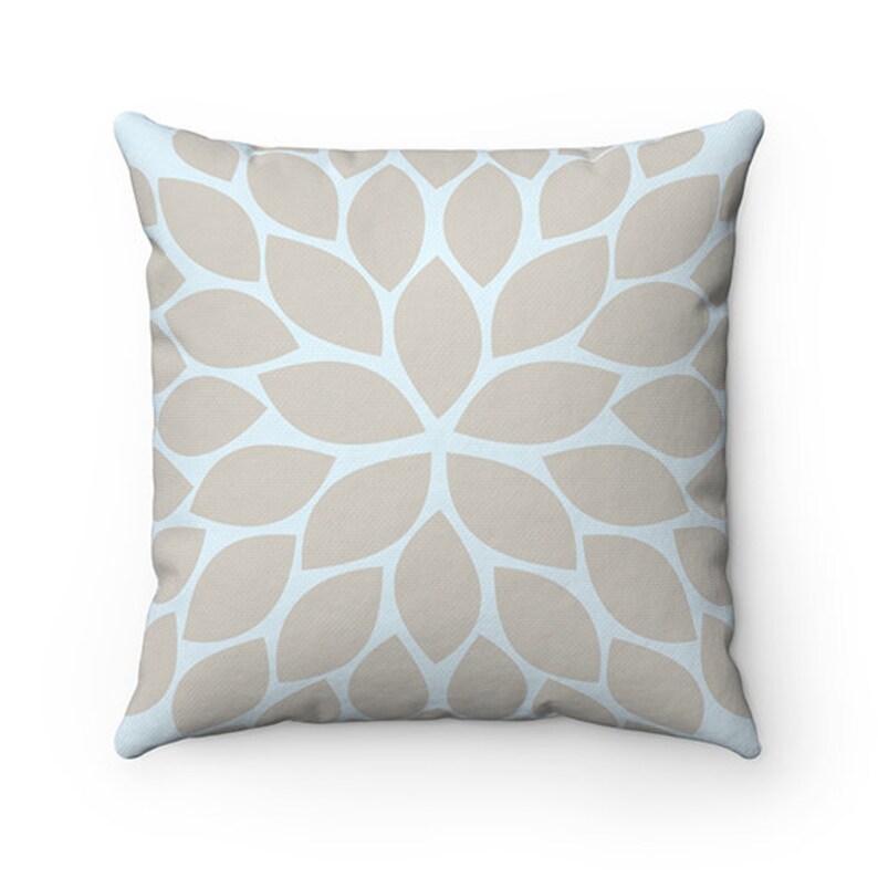 Puede incluir: Una almohada decorativa con un fondo azul claro y un patr&oacute;n floral beige.