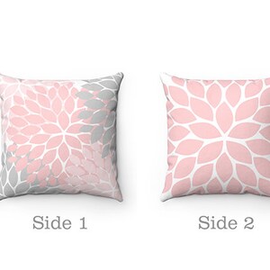 May include: Two-sided throw pillow with a pink and gray floral pattern. One side features a pink and gray floral design, while the other side is a solid pink floral pattern.