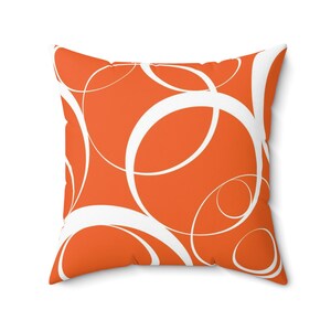 May include: Orange throw pillow with a white abstract pattern of overlapping circles.