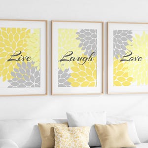 May include: Three framed prints with a yellow and gray floral design. The prints feature the words "Live", "Laugh", and "Love" in black text.