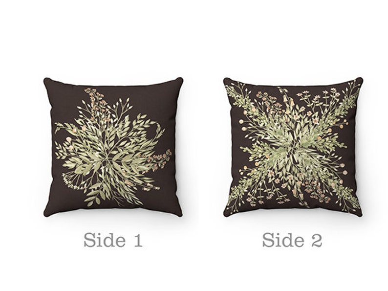 May include: Two square throw pillows with a dark brown background. Each pillow features a symmetrical floral design in shades of green and beige. The text "Side 1" and "Side 2" are below the pillows.